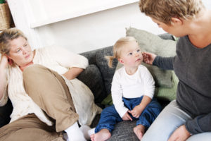 Malin sitter i soffan och klappar Agnes på kinden.